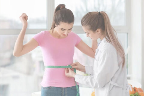 a doctor measuring a woman's waist with a measuring tape